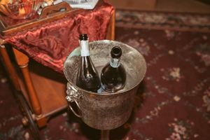 Two wine bottles chilling in vintage metal ice bucket on rustic wooden surface.