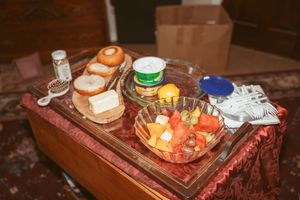 Appetizer and refreshment table with drinks and fruit platter displayed on wooden furniture.