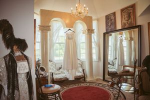Bright white interior room with antique furniture, ornate mirrors, and tall windows allowing natural light.