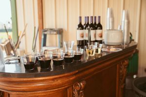 Wine bottles and glasses arranged on curved wooden bar counter.