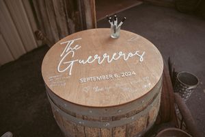 Wine barrel lids with handwritten text visible on their circular wooden tops in a dimly lit space.