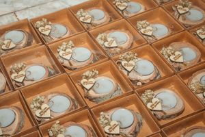 Rows of handmade heart-shaped clay soap dishes with textured floral designs arranged neatly on a wooden surface.