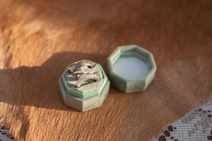 Two antique-style mint green hexagonal boxes with decorative details sit on a wooden surface.