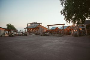 Wide angle shot of an empty asphalt parking area with low-rise commercial buildings and trees in the distance.