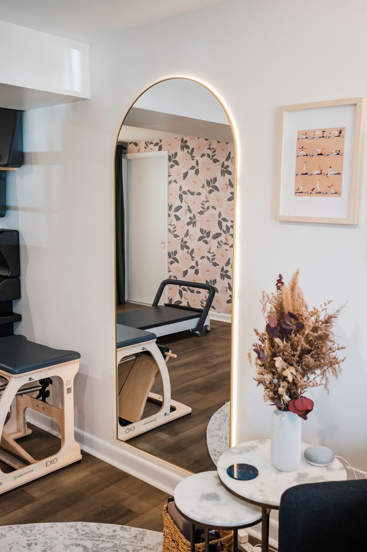 A black and white tuxedo cat lounges on hardwood flooring next to wooden display bins in a retail setting.