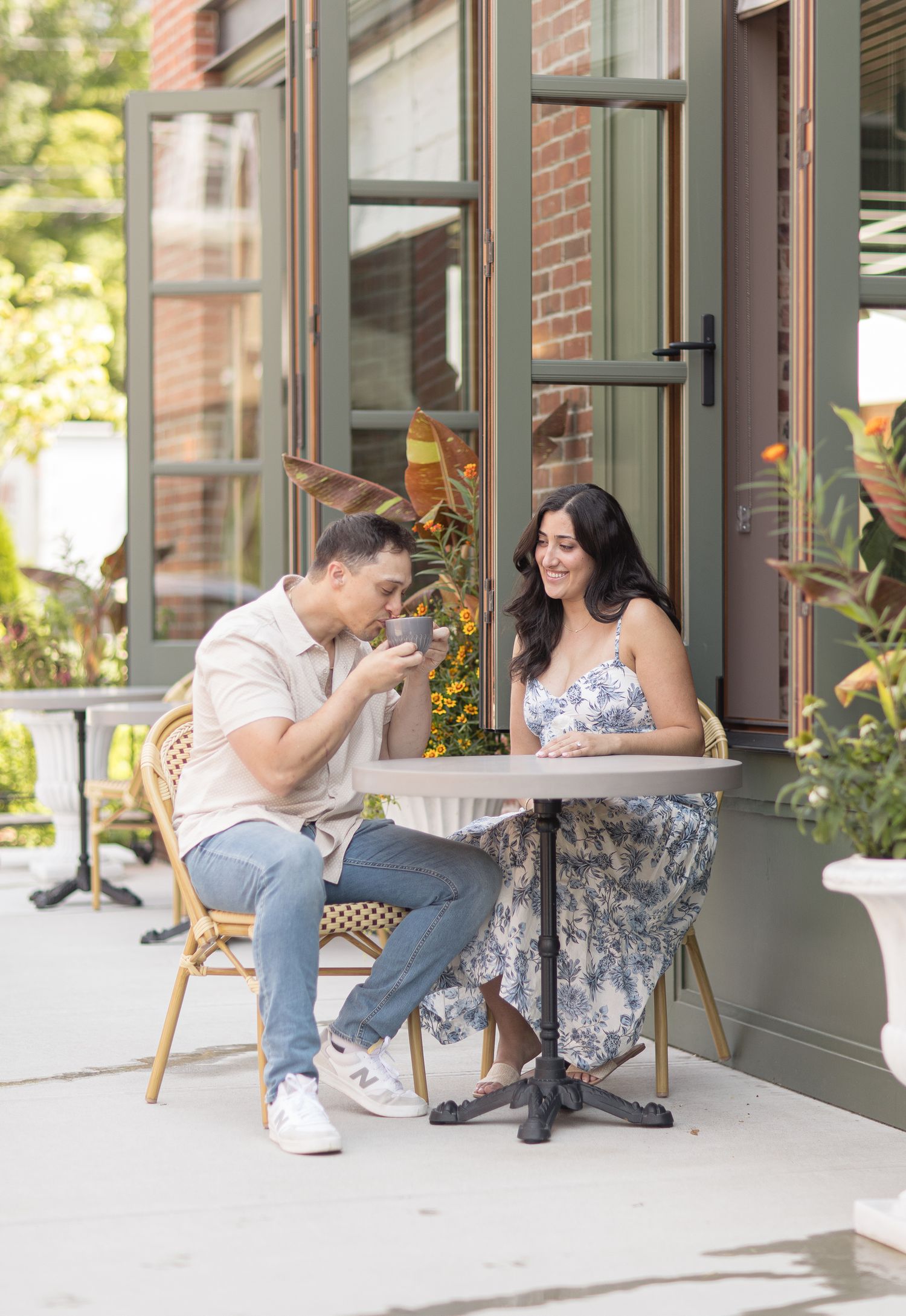 A couple enjoys coffee and conversation at an outdoor bistro table on a sunny afternoon.