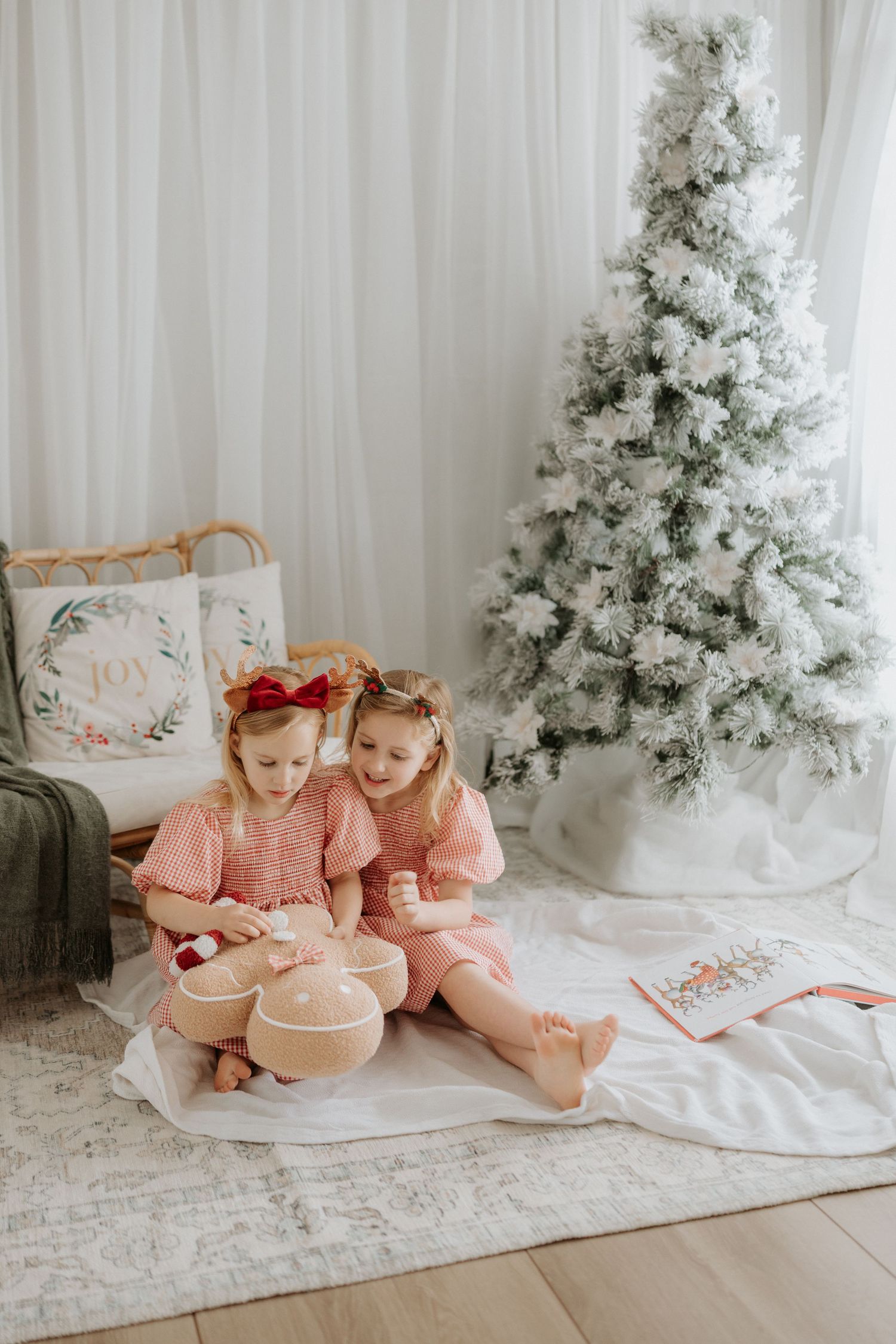 Four sequential photos show siblings sitting together in front of a white Christmas tree in neutral tones and soft lighting.
