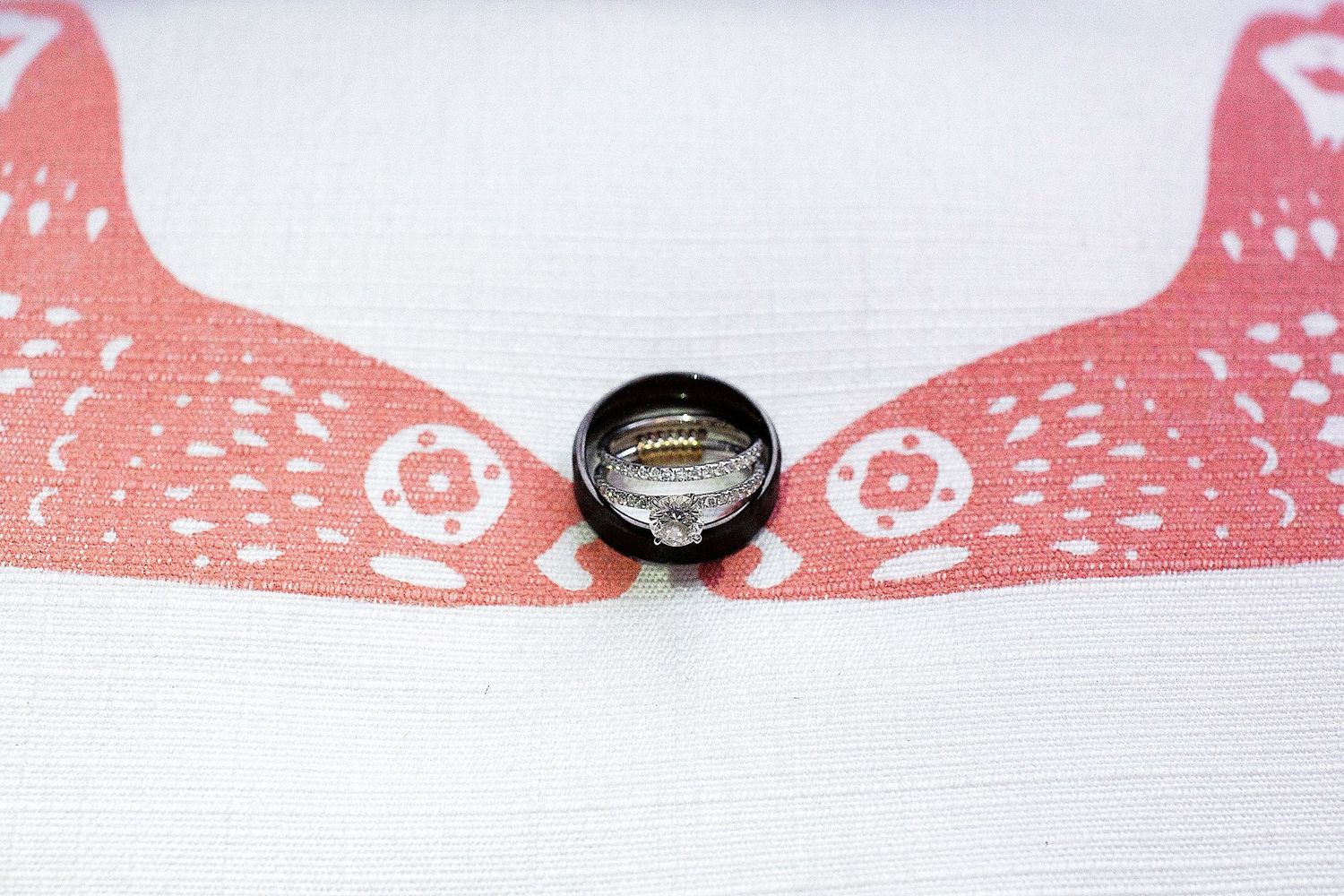 A wedding ring photographed against coral-colored paper creates a unique reflection effect.