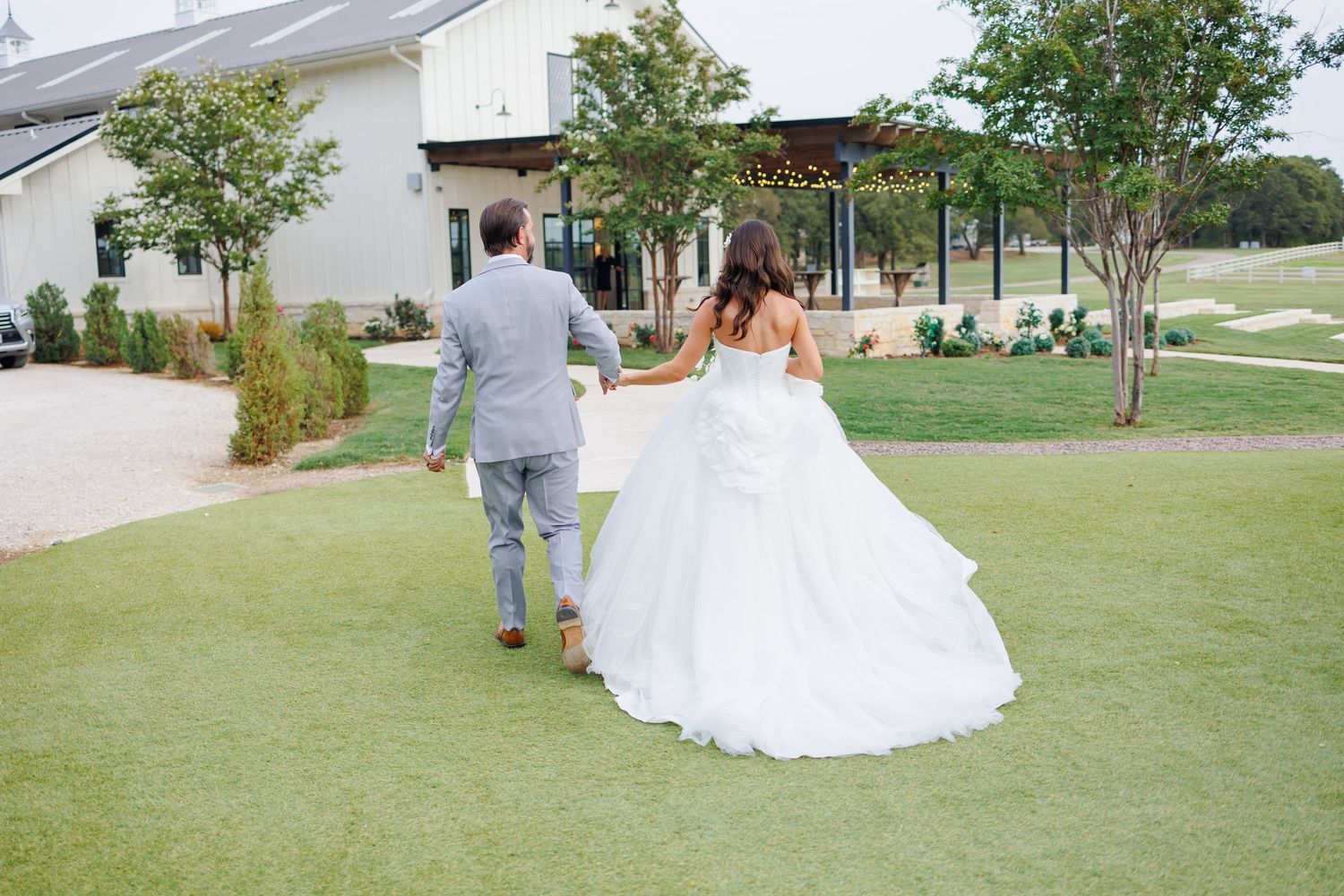 A couple walks toward Bella Cavalli during an outdoor wedding celebration in Dallas.