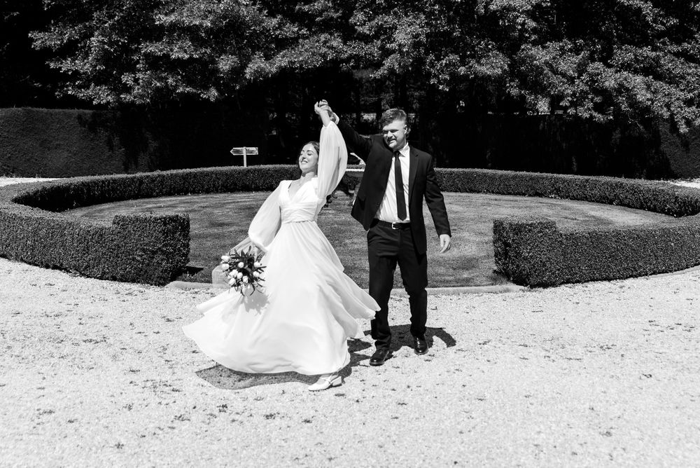 A joyful moment captured in black and white as a couple celebrates their wedding day in a manicured garden.