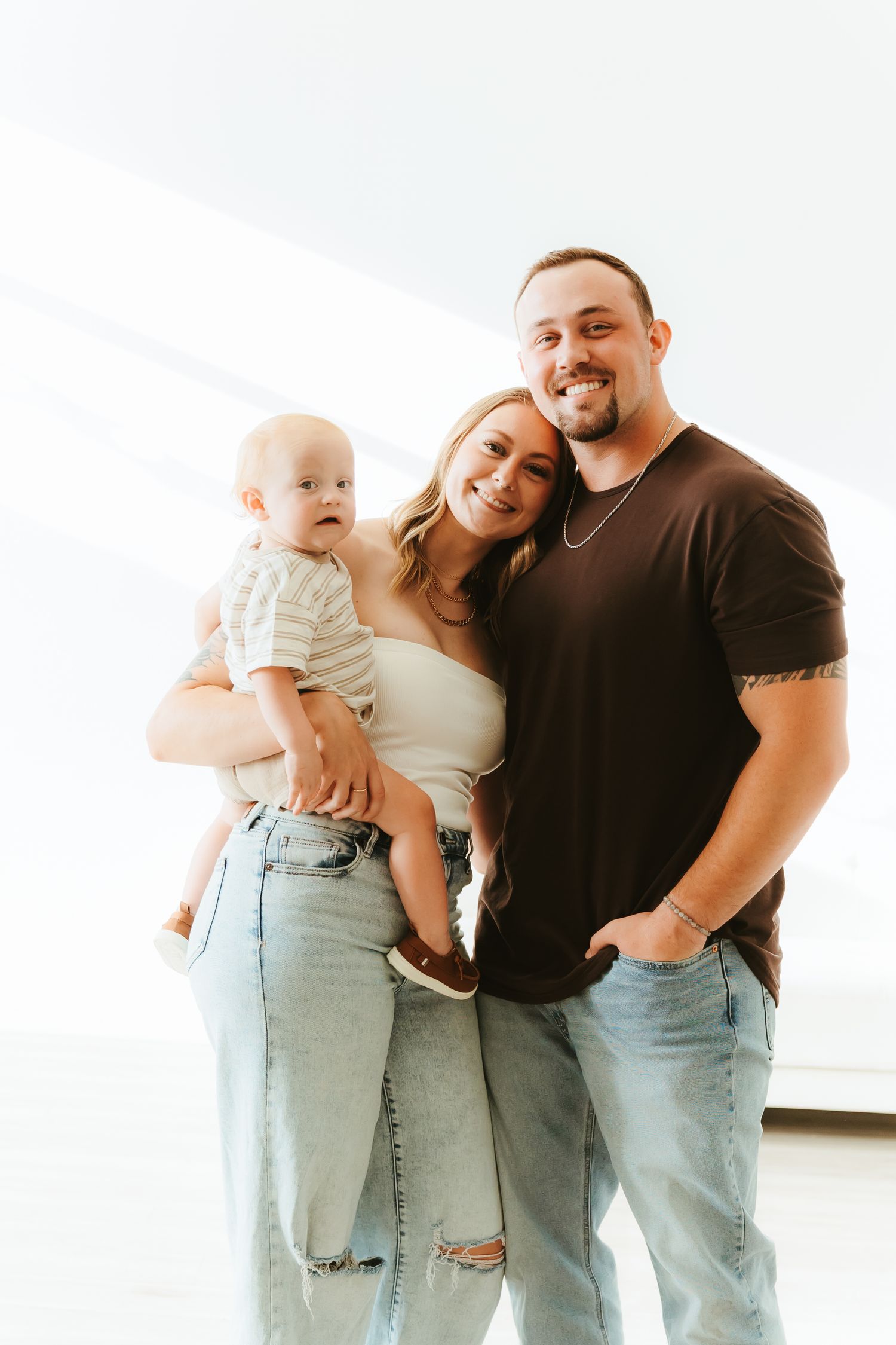 Happy family in matching casual outfits of jeans and black shirts poses together against white background.