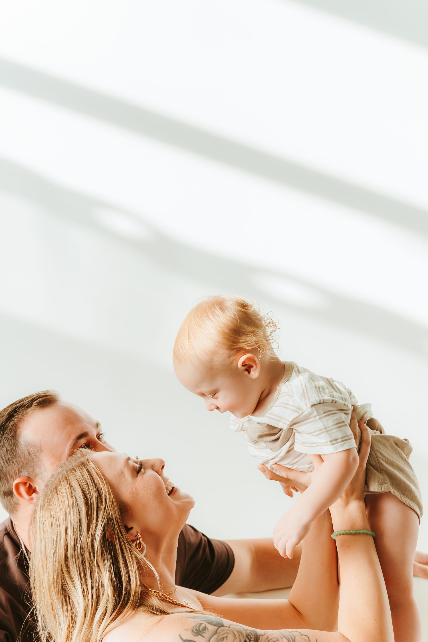 A collage of three photos showing a mother lifting and playing with her baby in a bright, white setting.