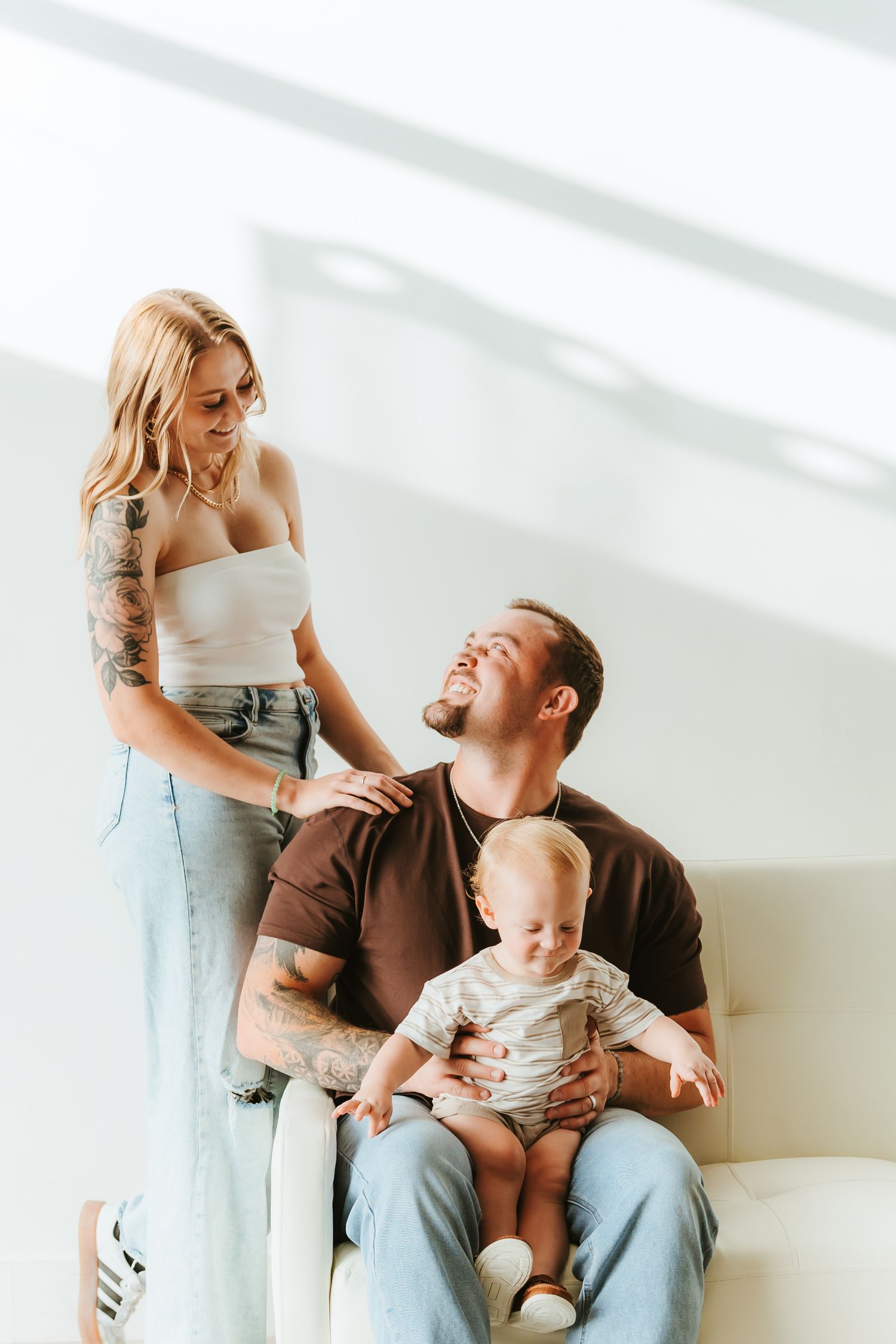 A family shares a joyful moment together in a bright, minimalist setting as they interact with their baby.