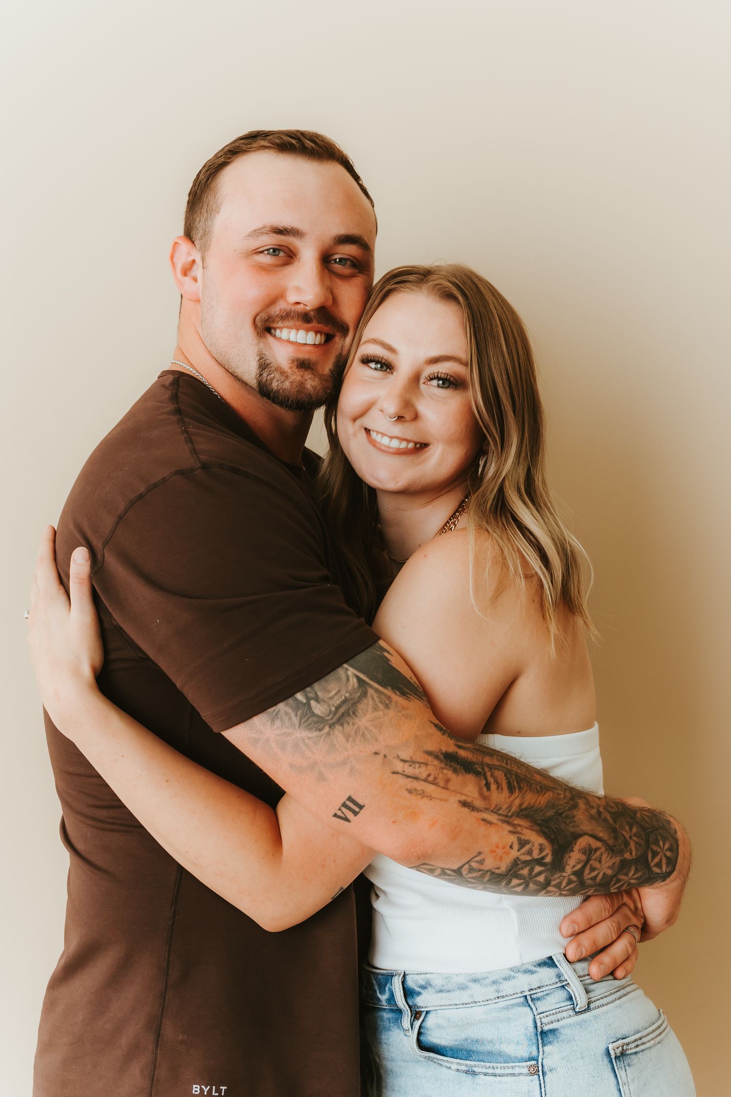 A tender moment captured between two people embracing against a neutral background in a casual photo shoot.