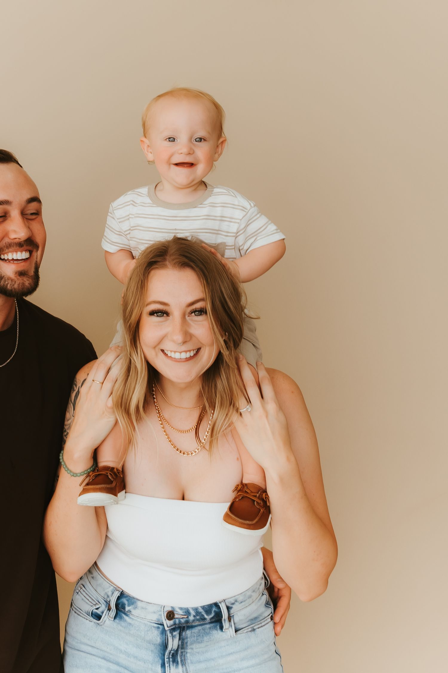 A family portrait against a beige background showing loving expressions and casual attire.