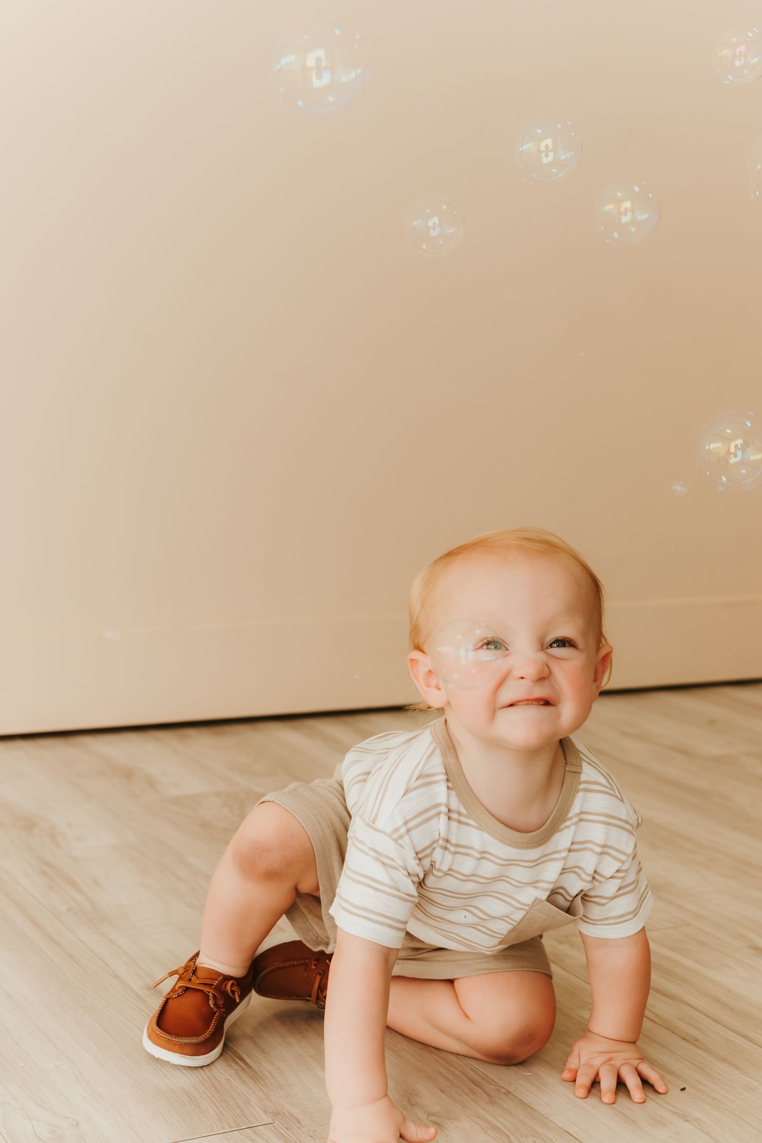 Baby in striped onesie crawls on hardwood floor in progressive motion shots.