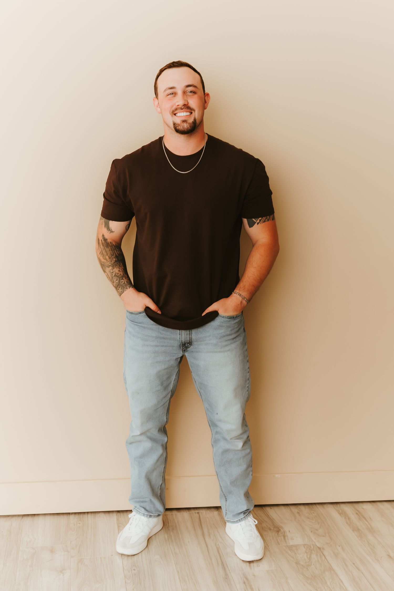Person in casual black t-shirt and light jeans poses against white background in four similar standing poses.