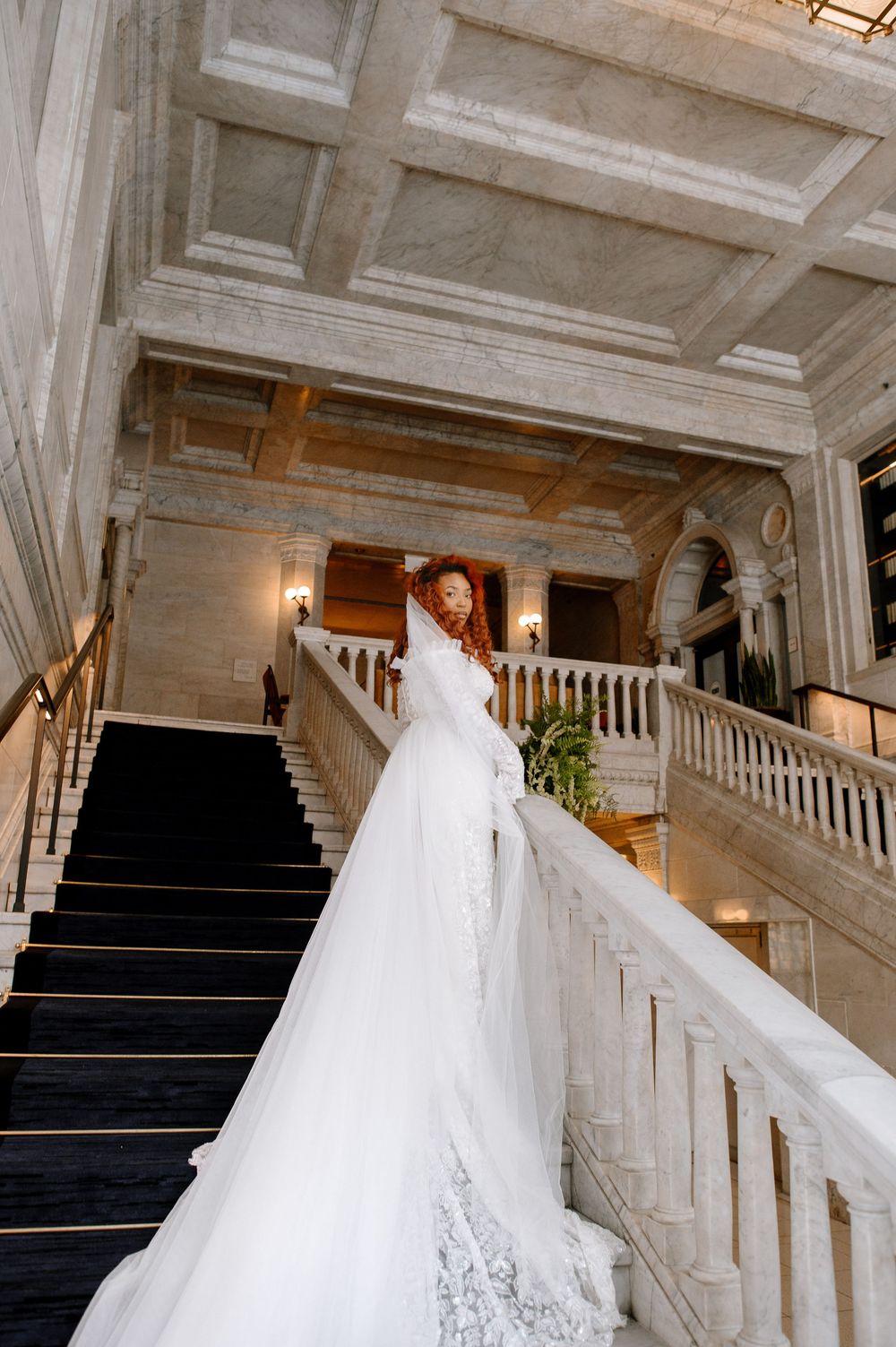 Architectural shots of a grand marble staircase with navy carpet and ornate white balustrades in an elegant venue.