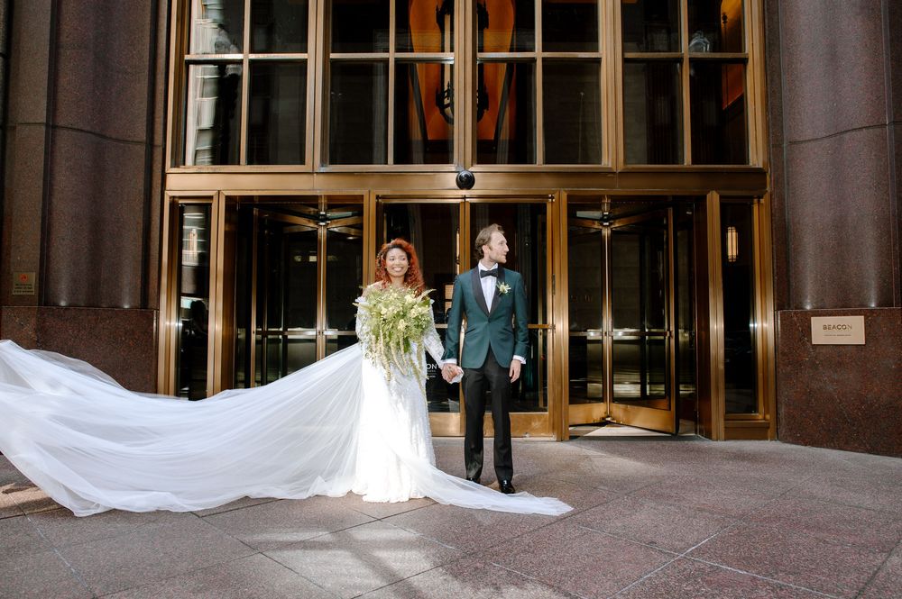 Wedding couple stands together with dramatic shadows cast on the building wall behind them.