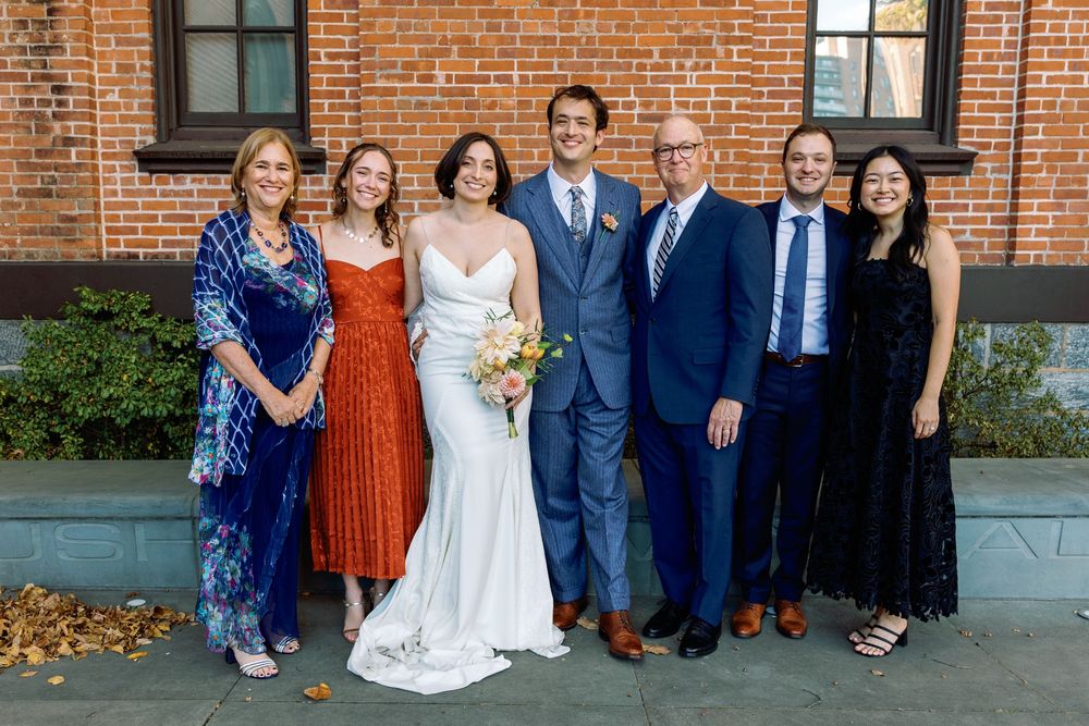 Wedding party posed for photos outside a classic brick building.
