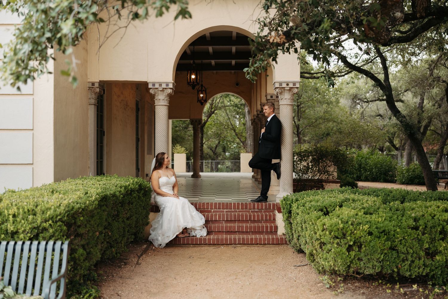 Elegant wedding venue with Spanish-style architecture features arched walkways, stone steps, and lush garden landscaping.