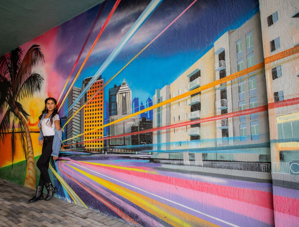 Girl posing for senior portraits in front of mural downtown fort lauderdale