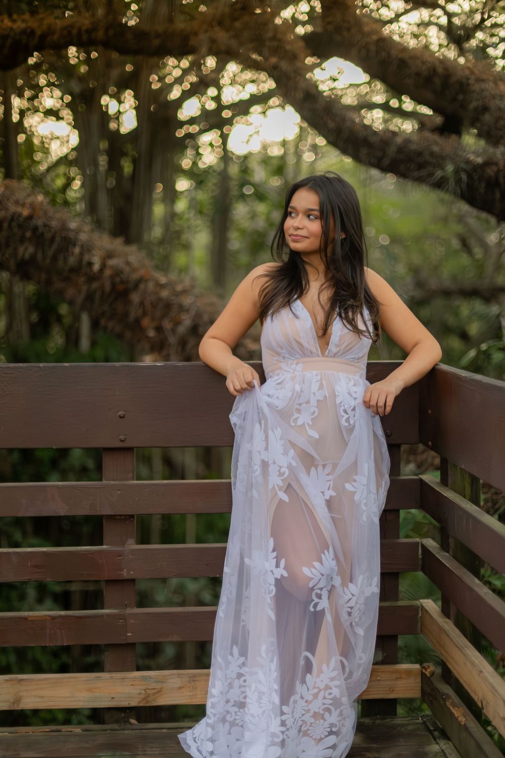 Girl posing for senior portraits at Tree tops Park on top of the treehouse