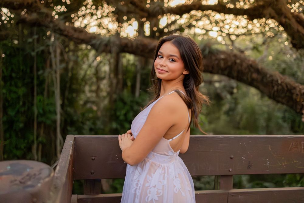 Girl posing for senior portraits at Tree tops Park on top of the tree house