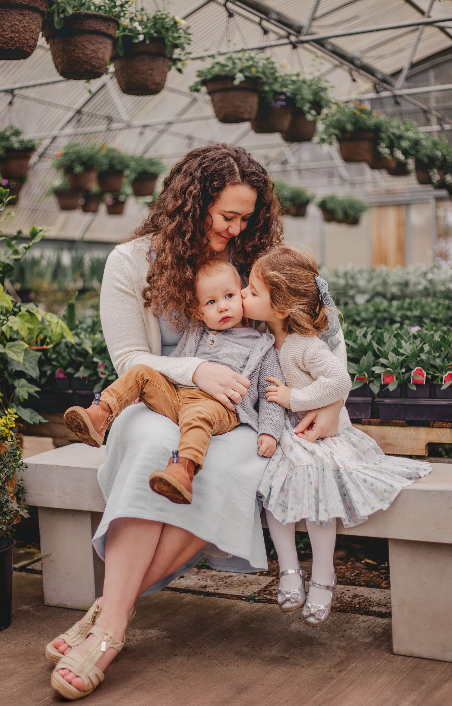 Mom and children sitting together during their greenhouse motherhood photoshoot at Christianson Nursery near Seattle WA