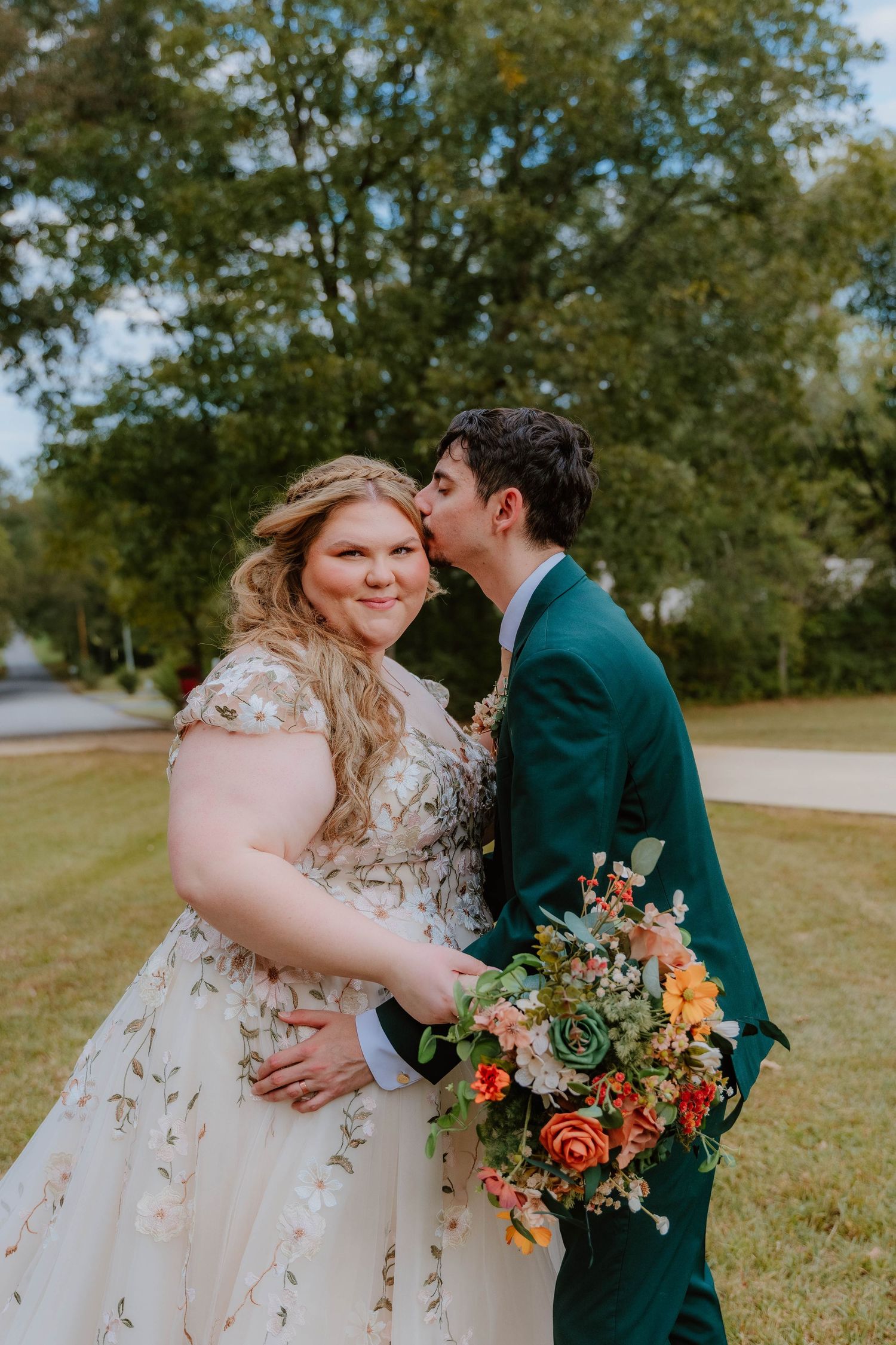 Romantic outdoor wedding portraits with a colorful bouquet and emerald green suit.