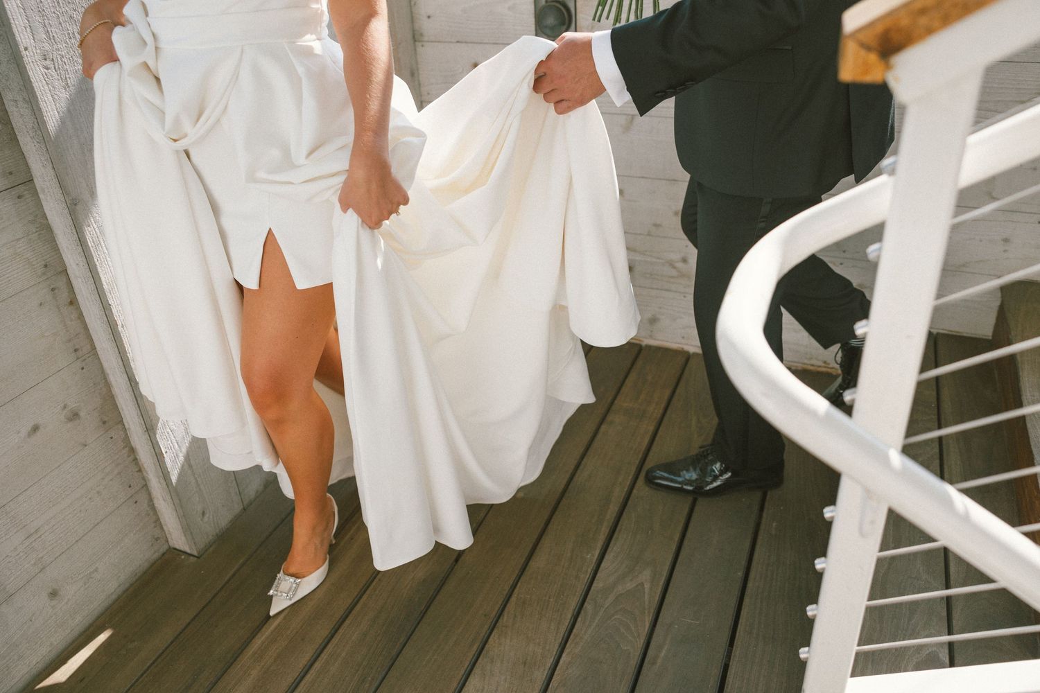 People in white formal attire standing on a wooden deck or boardwalk.