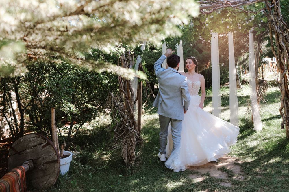 A couple dances under flowering trees during their outdoor wedding celebration.
