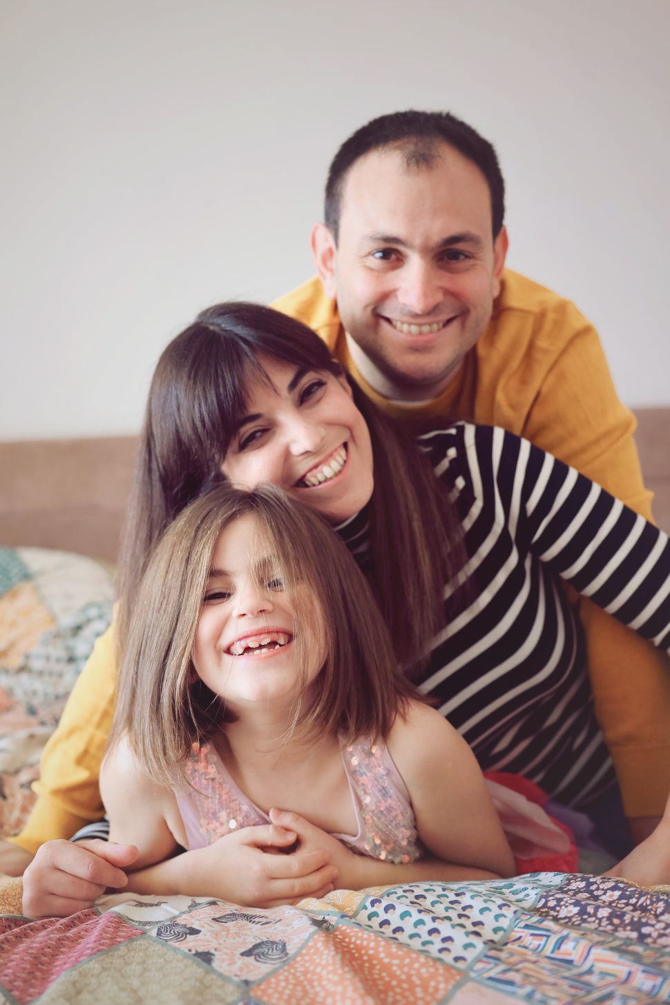 A family shares joyful moments together while relaxing on a patchwork quilt.