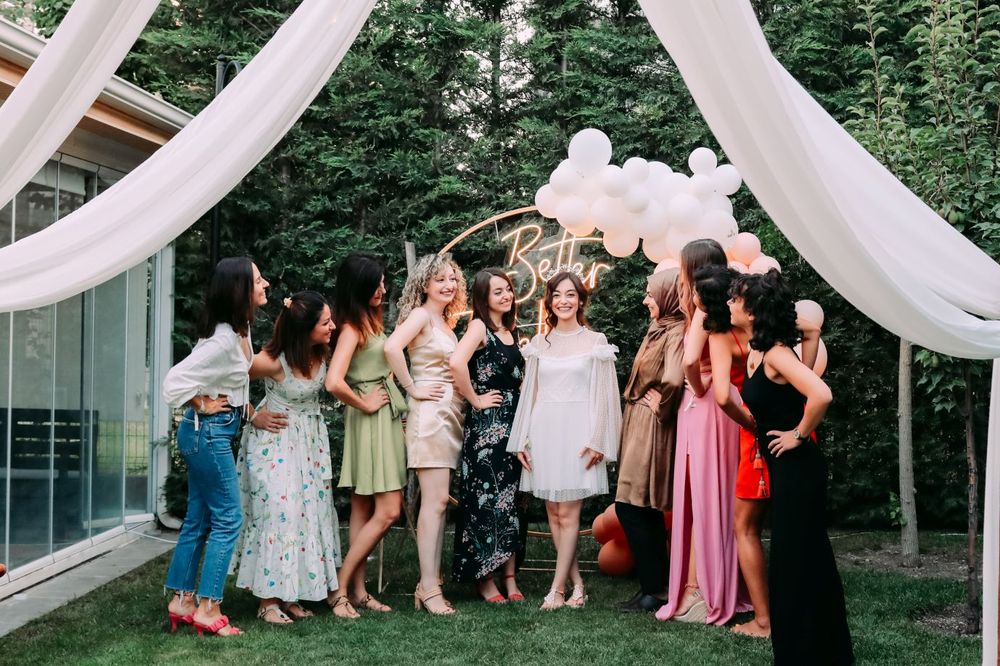 A group celebrates at an outdoor wedding under white draped fabric and trees.