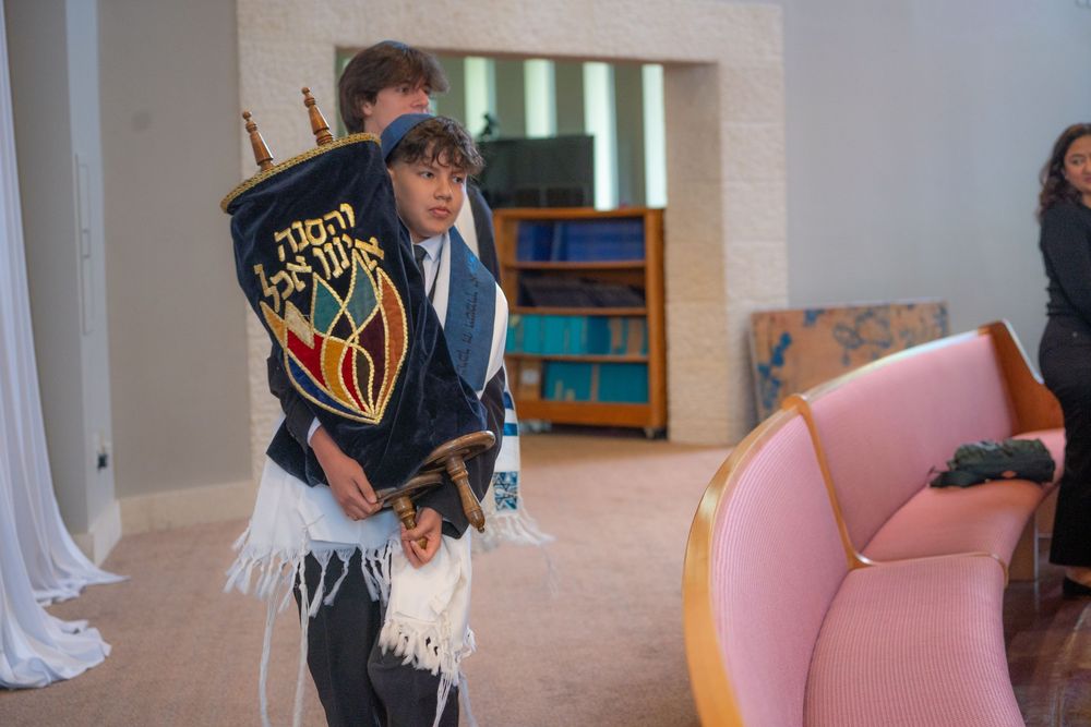 Boy carrying a Torah scroll during his Bar Mitzvah ceremony in a synagogue.