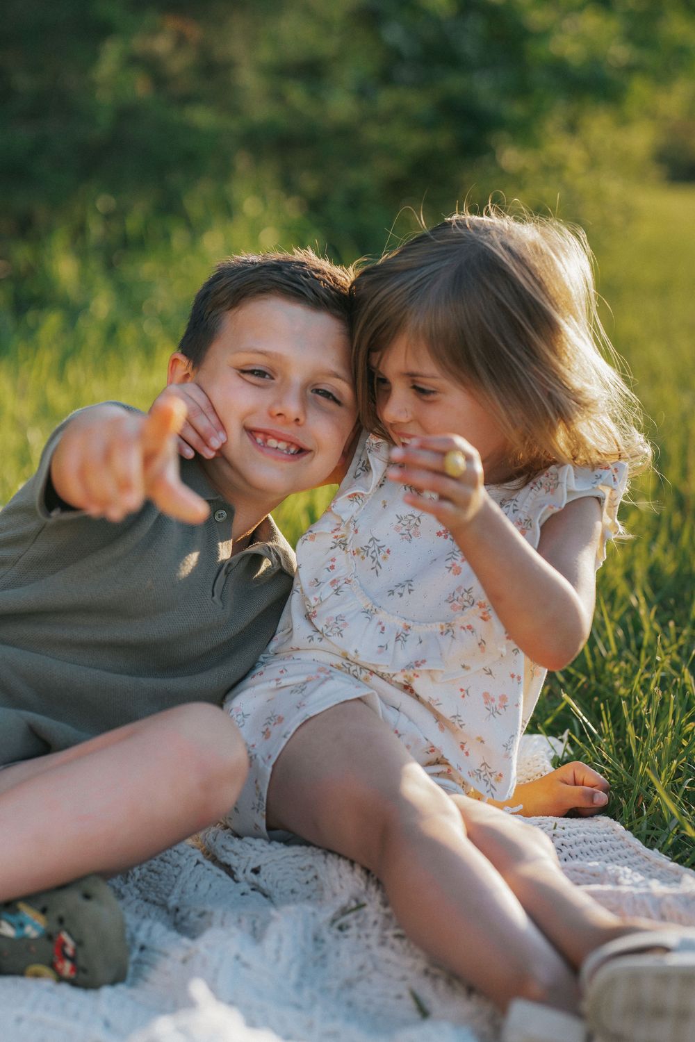 Two children laying in green grass on a summer day enjoying the outdoors together and playing.