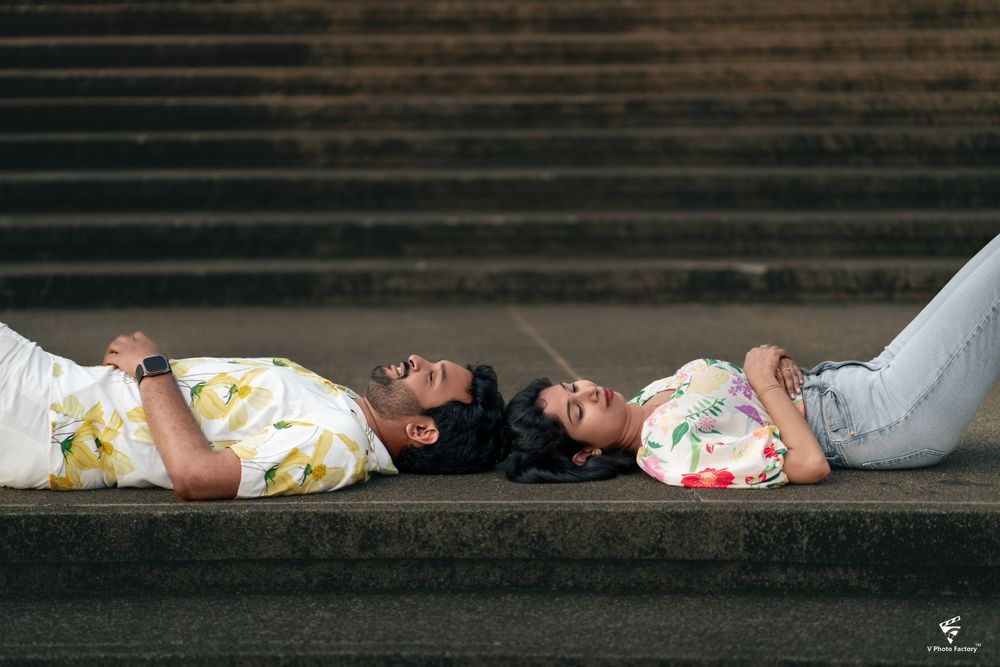 Couple lying on steps in casual floral outfits during a romantic photoshoot.