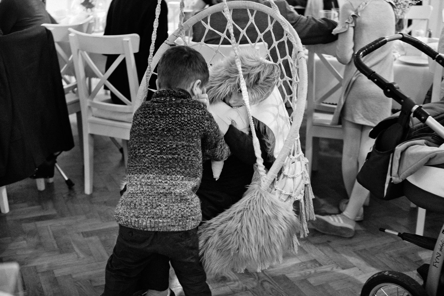 People standing near a dessert table with cakes at a party with white chairs visible in the background.