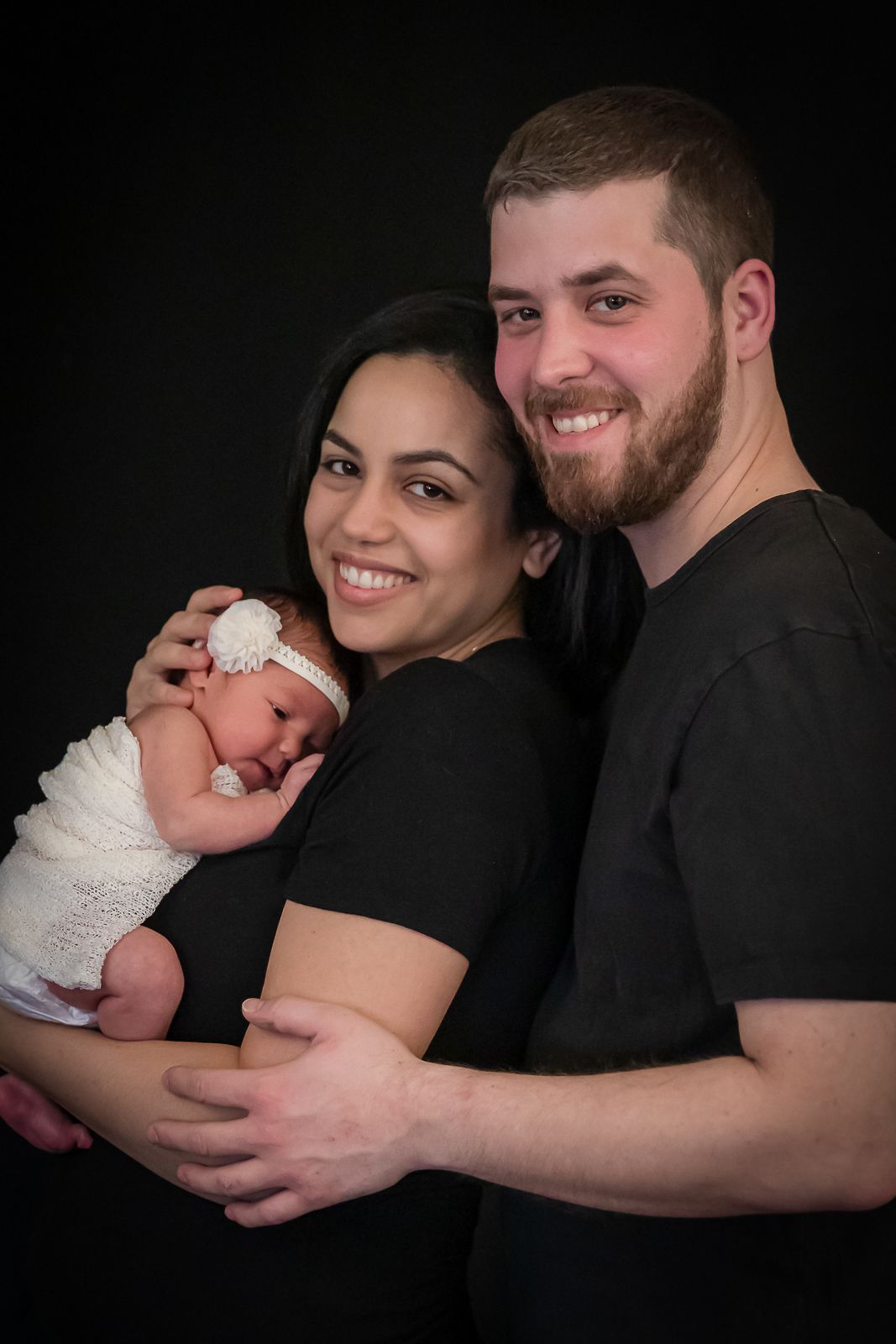 A family of four sharing tender moments together while gazing at their newborn baby in a series of connected photos.