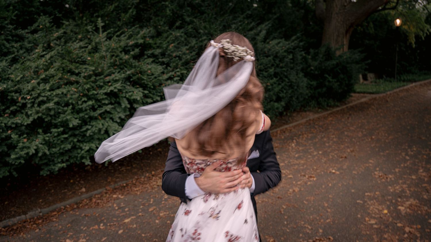 Groom lifting bride in a joyful embrace on their autumn wedding day.