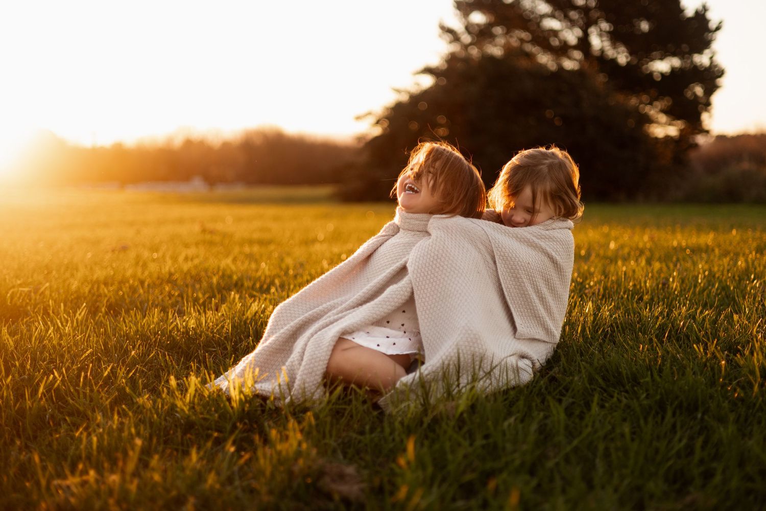 sisters cuddling together with blanket at Roto Kohatu Reserve christchurch