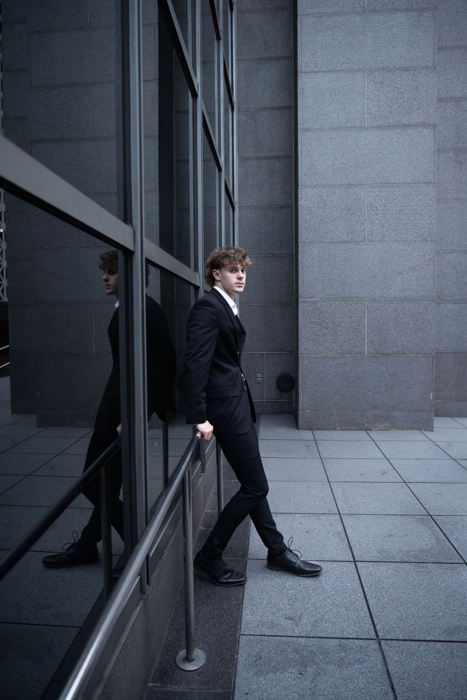 A sequence of black and white photos showing a person in business attire walking past a modern office building exterior.