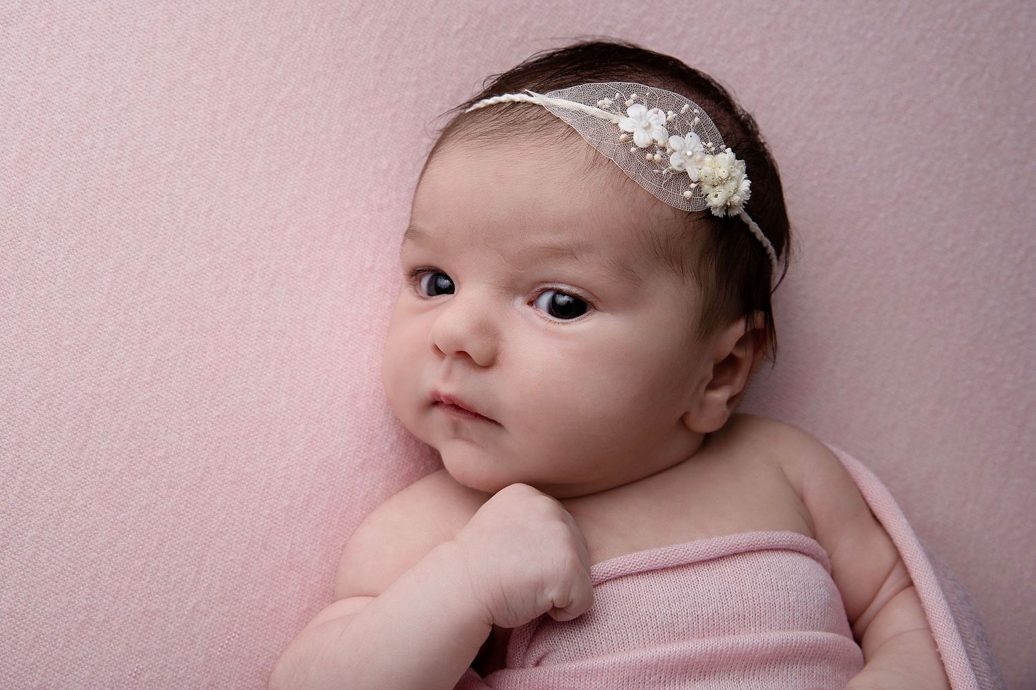 Sleeping newborn baby lying on soft beige blanket in artistic studio portrait series.