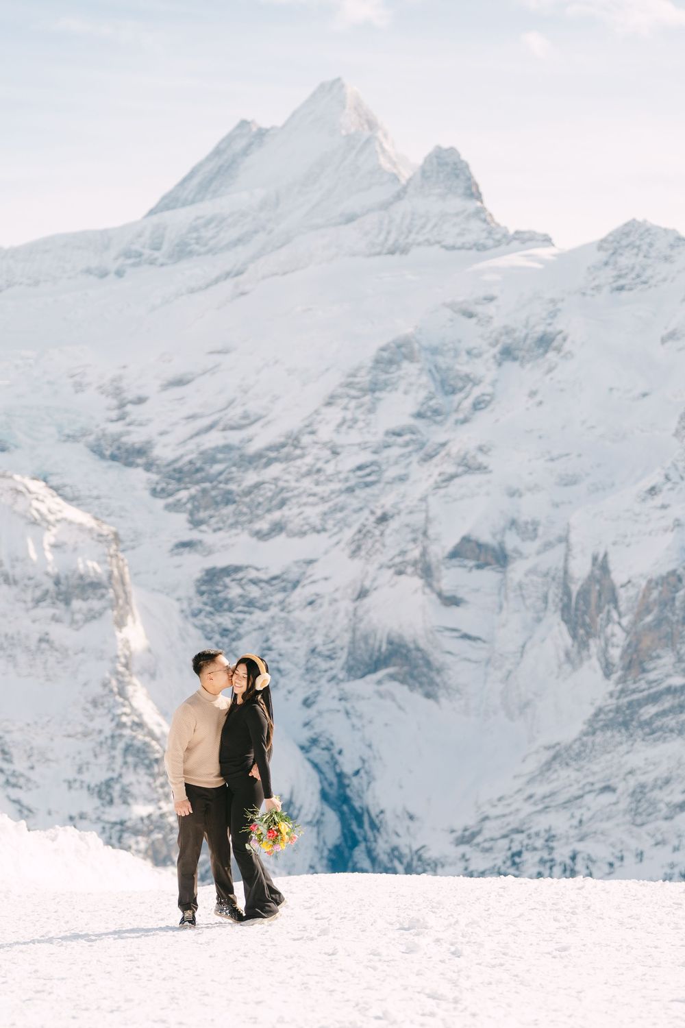 Snow-covered mountain peaks create a dramatic backdrop against a white winter landscape in the Swiss Alps.