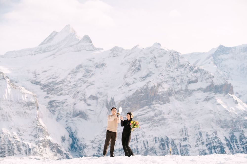 Skiers enjoying a scenic winter day on snowy mountain slopes with dramatic snow-capped peaks in the background.