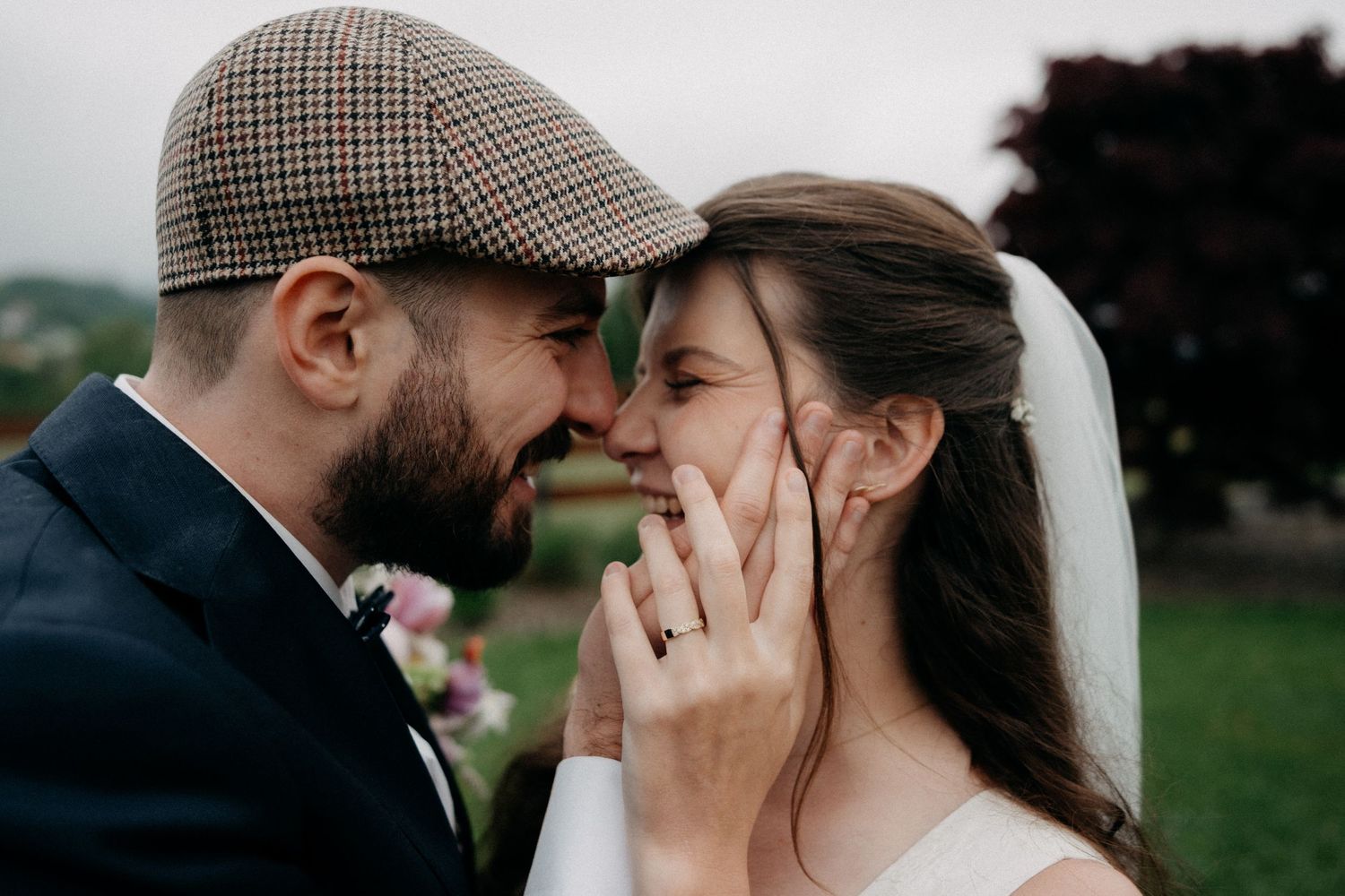 Romantic couple shares intimate kisses in outdoor wedding photos wearing formal attire and vintage-inspired hats.