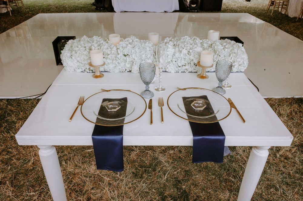 Sweetheart table with navy runners, gold cutlery, white hydrangeas, and personalized place settings.