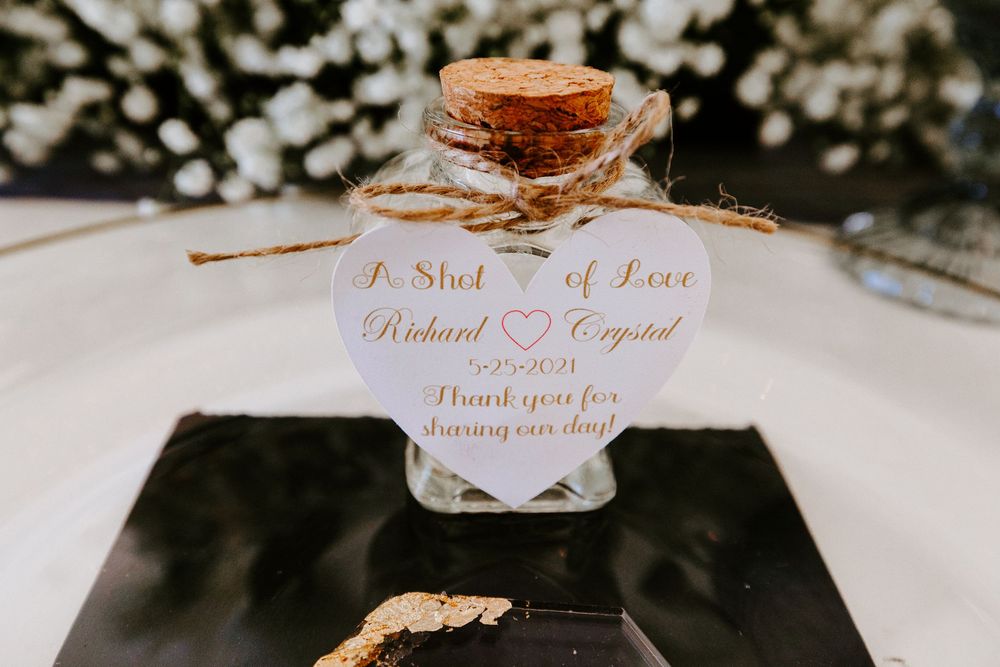 Wedding favor bottle with heart tag reading A Shot of Love for Richard and Crystal.