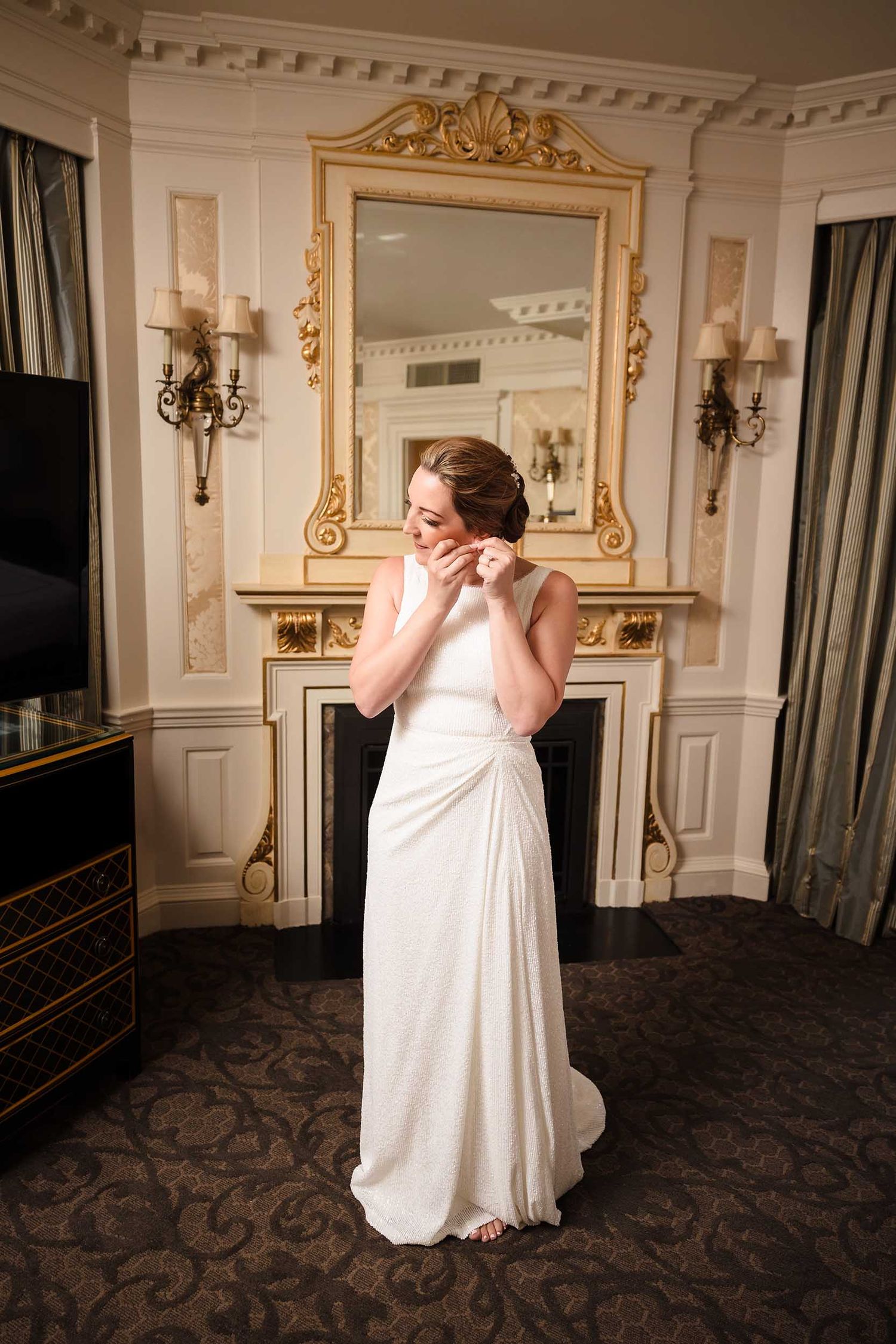 Bride putting on earrings in Judy Garland Suite at Lenox Hotel Boston with elegant interior details