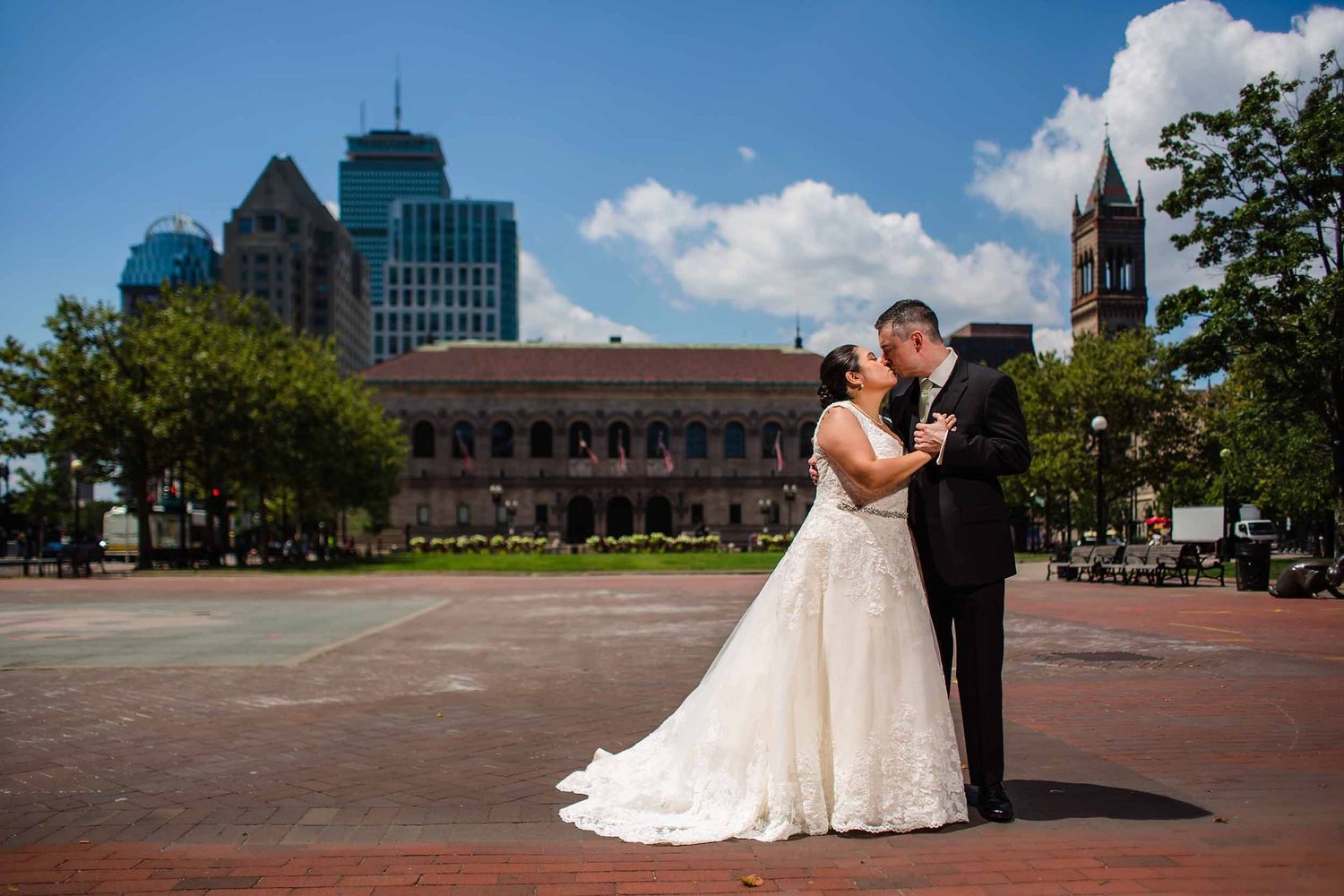 Bride and groom kissing in Copley Square in front of the Boston Public Library during wedding portrait